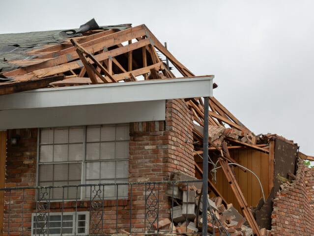 Damaged house following a storm, with exposed beams and fallen brickwork