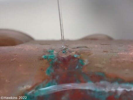 a close up of a chemical being added to a copper plumbing pipe