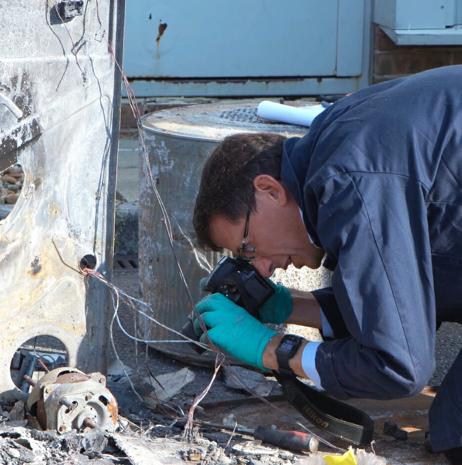 One of our forensic investigators taking photo graphs with a digital camera on a scene from what could be a fire