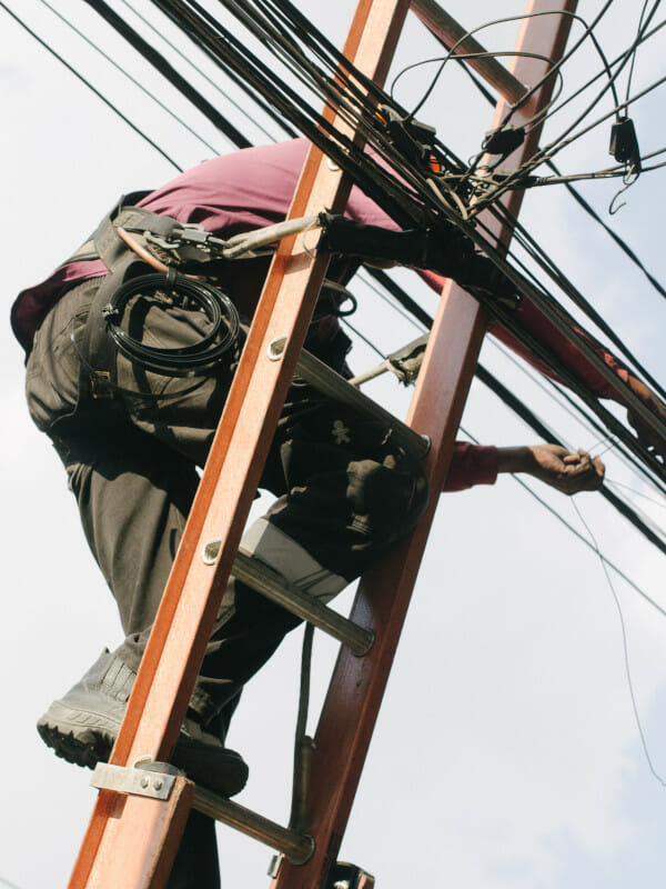 Man on ladder fixing cables