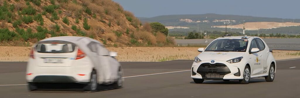 Two Toyota Yaris' in white driving towards each other to simulate the automated breaking system