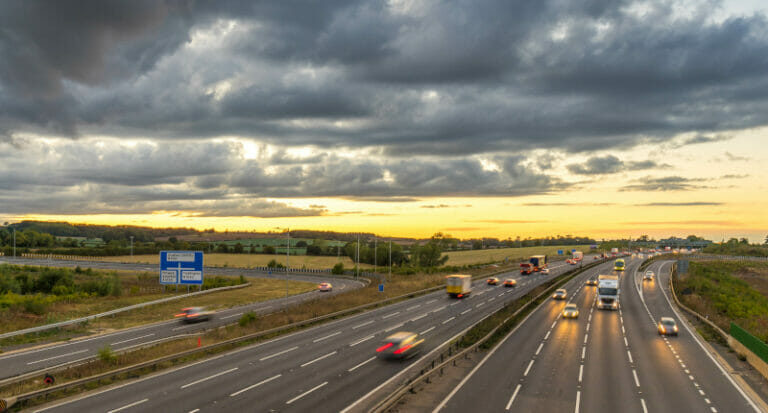 a photograph of a motorway with the sun setting in the background, UK
