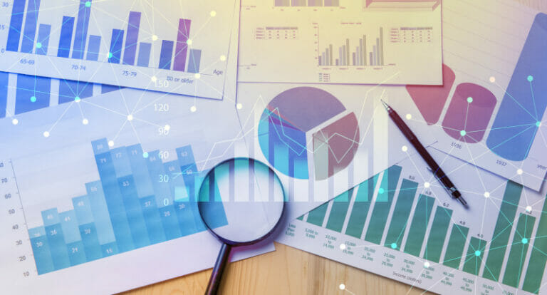 Magnifying glass and documents with analytics data lying on table,selective focus