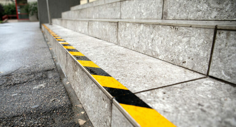 Yellow anti slip warning tape on stairs outdoors for safety. Pub