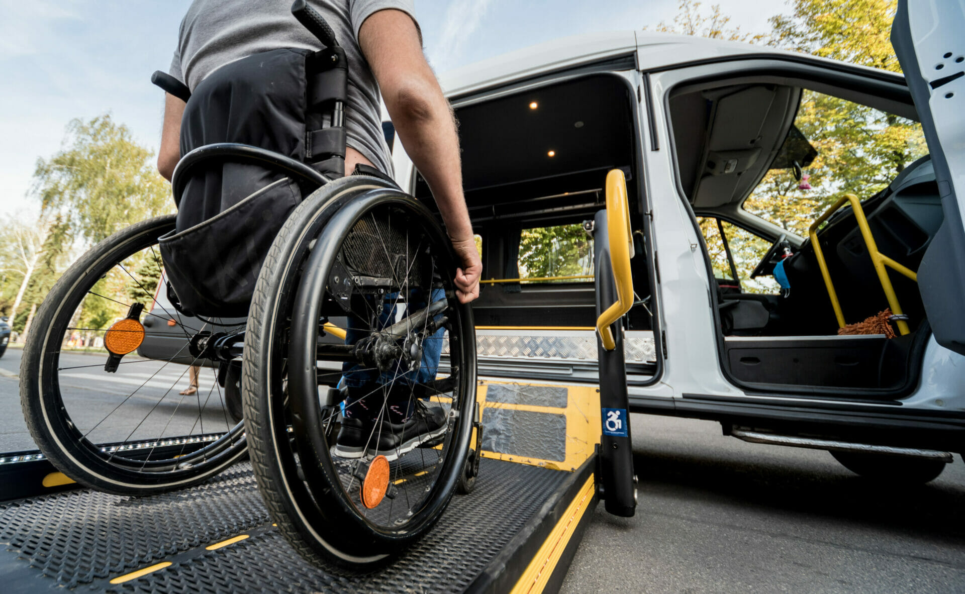 A man in a wheelchair moves to the lift of a specialized vehicle for people with disabilities