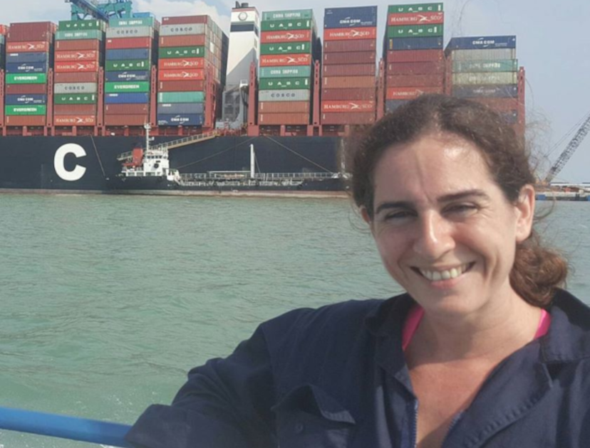 Our marine specialist Sophie Parsons on a boat in a dockyard with shipping containers behind her