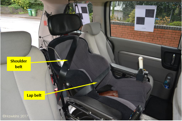 An interior view of the wheelchair strapped into the car. It gives an example of the shoulder belt and the lap belt.