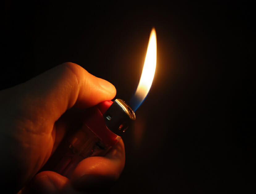 A hand igniting a cigarette lighter