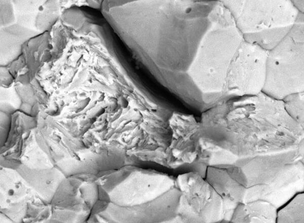 A region of failure that shows the crystalline appearance of hydrogen embrittlement and the more jagged appearance of ductile failure by micro-void coalescence.