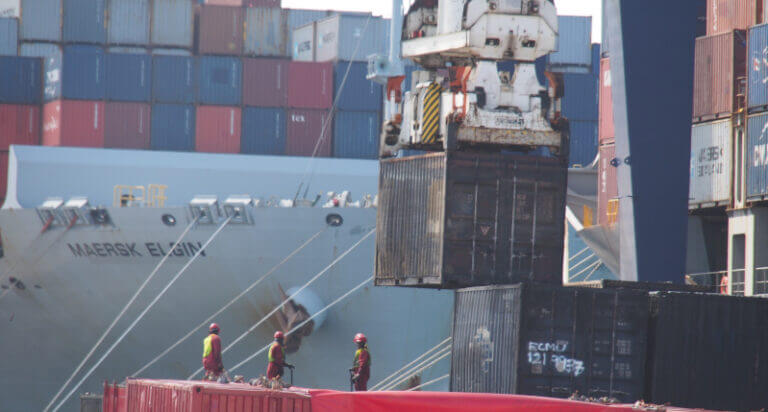 Reach stacker crane moving containers on a ship