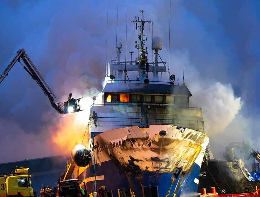 Ship on fire with a firefighter extinguishing the flames from above