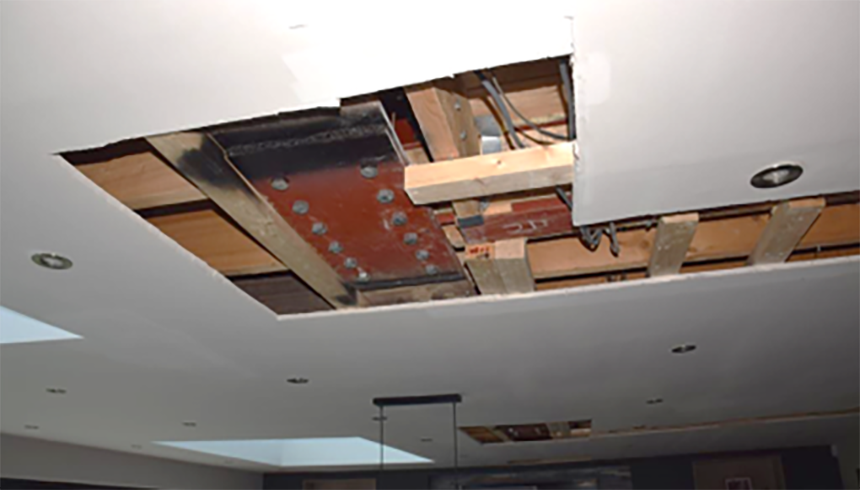 Cracking in the wall above supported on spliced steel beam with insufficient strength and stiffness for the span