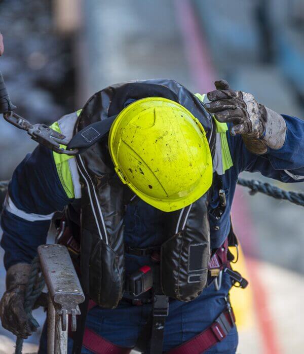A construction worker bending down after being hit in the head from falling debris